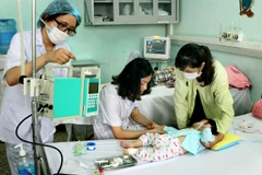 Nhân viên y tế chăm sóc cho trẻ bị rối loạn tiêu hóa. (Ảnh: TTXVN/Vietnam+)