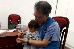 Giáo sư phẫu thuật thẩm mỹ Oh KapSung khám cho một bệnh nhi có 6 ngón tay. (Ảnh: PV/Vietnam+)