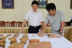 Các nhà nghiên cứu chia sẻ thông tin về những hiện vật được khai quật. (Ảnh: Quốc Dũng/TTXVN)