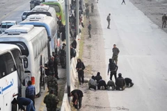 Xe buýt chở các tay súng nổi dậy cùng gia đình rời khỏi thành phố Harasta, ngoại ô Đông Ghouta ngày 22/3. (Ảnh: THX/TTXVN)