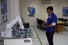 Các kỹ sư điều chỉnh hoạt động của robot tại phòng thực hành robot tự động hóa Trung tâm đào tạo và chuyển giao công nghệ Việt-Nhật. (Ảnh: Tiến Lực/TTXVN) 