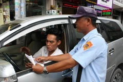Nhân viên tổ thu phí xe ôtô quận 1 hướng dẫn lái xe cách thanh toán phí qua ứng dụng My Parking trên đường Thủ Khoa Huân. (Ảnh: Tiến Lực/TTXVN)