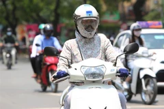 Người dân thủ đô chống chọi với nắng nóng bằng trang phục kín mít. (Ảnh: Thành Đạt/TTXVN)