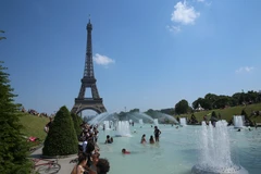 Người dân tránh nắng nóng bên vòi phun nước ở Paris, Pháp. (Nguồn: THX/TTXVN)