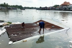 Người dân tháo dỡ tài sản bị chìm dưới sông do sạt lở. (Ảnh: Thanh Liêm/TTXVN)