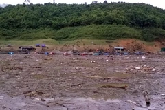 Do mưa lớn, nước dâng cao, bùn đất và rác từ các nơi đổ về nên việc tìm kiếm thi thể em Hoàng Thị Nhàn gặp nhiều khó khăn. (Nguồn: TTXVN)