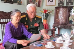 Đại tá Trịnh Xuân Ứng xem lại những kỷ vật xưa. (Ảnh: Hải Yến/TTXVN)