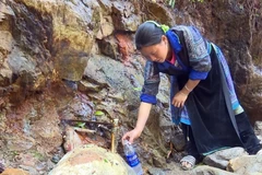 Người dân lấy nước tại mạch nước ngầm ở khu vực chân núi. (Ảnh: Hữu Quyết/TTXVN)