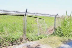 Hàng rào B40 bảo vệ đường cao tốc bị phá, lấy lối đi lên cao tốc. (Ảnh: Nam Thái/TTXVN)