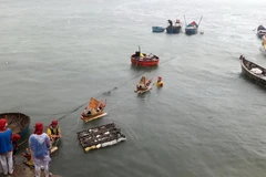 Đưa mô hình thuyền và hình nhân thế mạng để thả trôi ra biển - nghi lễ quan trọng trong buổi lễ. (Ảnh: Sỹ Thắng/TTXVN)