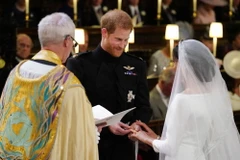 Chú rể Harry (giữa) trao nhẫn cho cô dâu Meghan Markle (phải) tại hôn lễ. (Nguồn: AFP/TTXVN)