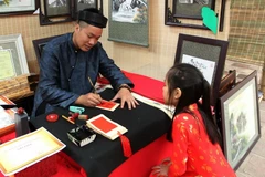 Du khách xin chữ tại Phố ông Đồ. (Ảnh: Quốc Khánh/TTXVN)