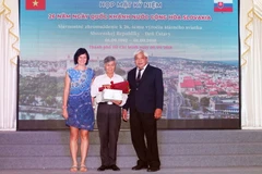 Bà Ivana Belcáková, Đại biện lâm thời Đại sứ quán Cộng hòa Slovakia tại Việt Nam tặng hoa vinh danh ông Trần Xuân Đàm (giữa), người đã tham gia biên soạn cuốn Từ điển Tiệp Khắc-Việt Nam. (Ảnh: Xuân Khu/TTXVN)