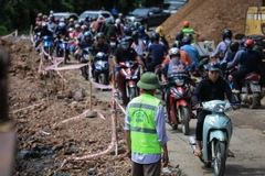 Người và phương tiện giao thông di chuyển chậm nối nhau đi qua điểm sạt lở tại dốc Cun, Km79+335, Quốc lộ 6, thuộc địa phận phường Thống Nhất, thành phố Hòa Bình. (Ảnh: Trọng Đạt/TTXVN)