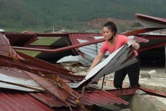 Người dân bãi ngang Quảng Đông (huyện Quảng Trạch) lợp lại mái nhà sau bão. (Ảnh: Đức Thọ/TTXVN)