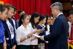 Đại biện lâm thời Đại sứ quán Việt Nam tại Lào, ông Nguyễn Thanh Tùng trao học bổng cho các con em Việt kiều. (Ảnh: Phạm Kiên/TTXVN/)