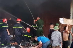 Lực lượng cảnh sát và công nhân khẩn trương dập tắt đám cháy. (Ảnh: Văn Đức/TTXVN)