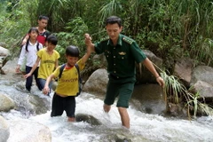 Bộ đội biên phòng giúp học sinh các bản thuộc xã Pa Vệ Su vượt suối đến trường đúng ngày khai giảng năm học mới. (Ảnh: Nguyễn Hoàng/TTXVN)