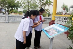 Học sinh quét mã QR để tìm hiểu thân thế, sự nghiệp nhà văn Nam Cao tại khu lưu niệm. (Ảnh: Nguyễn Chinh/TTXVN)