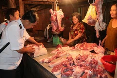 Lực lượng chức năng kiểm tra buôn bán thịt lợn tại các chợ xã. (Ảnh: Huỳnh Phúc Hậu/TTXVN)