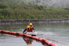 Lực lượng chức năng kiểm tra phao ngăn dầu tại Nhà máy nước sông Đà. (Ảnh: Thanh Hải/TTXVN)