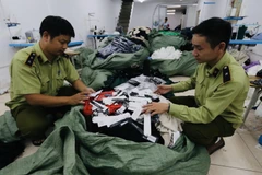 Lực lượng chức năng kiểm tra số hàng may mặc nhập khẩu được thay thế bằng nhãn mác IFU. (Ảnh: Trần Việt/TTXVN)