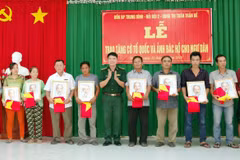 Lãnh đạo bộ đội biên phòng Sóc Trăng trao tặng cờ và ảnh bác Hồ cho ngư dân vùng ven biển Sóc Trăng. (Ảnh: Trung Hiếu-TTXVN)