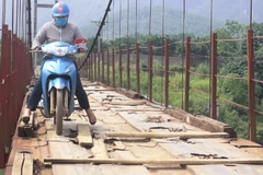 Người dân lưu thông khó khăn trên cầu treo xuống cấp. (Ảnh: Thanh Hải/TTXVN)