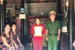 Đại diện Công an tỉnh Tây Ninh trao quyết định truy thăng cấp hàm từ hạ sỹ lên trung sỹ cho gia đình chiến sỹ Trần Văn Lành. (Ảnh: Lê Đức Hoảnh/TTXVN)