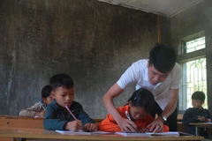 Thầy giáo Hoàng Văn Duy hướng dẫn học sinh viết bài tại điểm trường Hò Lù, xã Khánh Xuân (Bảo Lạc, Cao Bằng). (Ảnh: Chu Hiệu/TTXVN)