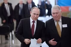  Đương kim Tổng thống Nga Vladimir Putin (trái) bỏ phiếu tại điểm bầu cử ở Moskva ngày 18/3. (Nguồn: THX/TTXVN)