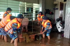 Cán bộ, chiến sỹ Hải đội 102 giúp bà con dọn dẹp nhà cửa khi nước rút. (Ảnh: TTXVN)