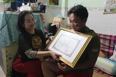Bà Vy Vũ Hồng Thảo, Phó Giám đốc Sở Nội vụ tỉnh Đồng Nai đến nhà riêng trao tặng bằng khen của Chủ tịch UBND tỉnh cho anh Văn Viết Cường vì đã có thành tích trong truy bắt tội phạm. (Ảnh: Lê Xuân/TTXVN)