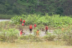 Lực lượng cứu hộ tổ chức tìm kiếm thi thể hai nạn nhân bị nước cuốn trôi mất tích. (Ảnh: Đậu Tất Thành/TTXVN)