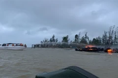 Lực lượng chức năng tại hiện trường khống chế đám cháy và di chuyển các thuyền tới khu vực an toàn. (Ảnh: Đoàn Hữu Trung/TTXVN)