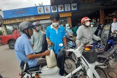 Người dân mang can đi mua xăng. (Ảnh: TTXVN)