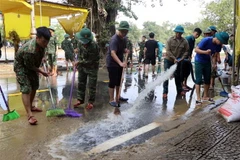 Các lực lượng tham gia dọn dẹp bùn non sau khi nước lũ rút tại nhiều tuyến đường của thành phố Huế. (Ảnh: Đỗ Trưởng/TTXVN)