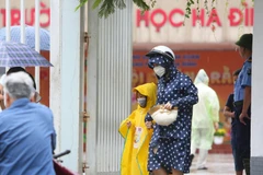 Các bậc phụ huynh đón con nhỏ luôn đeo khẩu trang tại Trường Tiểu học Hạ Đình, cách hiện trường vụ cháy Nhà xưởng Công ty Rạng Đông chưa đến 1km. (Ảnh: Thành Đạt/TTXVN)