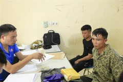 Hai đối tượng cùng tang vật tại cơ quan điều tra. (Ảnh: Xuân Tư/TTXVN)