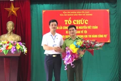 Phó Chánh án TAND tỉnh Hà Giang Trương Huy Huân tặng hoa cho ông Nguyễn Viết Xuân. (Ảnh: Minh Tâm-TTXVN)