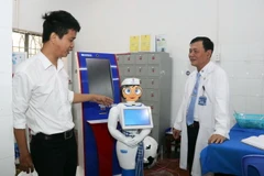 Kỹ sư Võ Hồng Quân, phụ trách Trung tâm Công nghệ thông tin, Bệnh viện Quân dân y miền Đông (trái) giới thiệu robot thông minh Cô Tấm hỗ trợ người bệnh. (Ảnh: Xuân Khu/TTXVN)