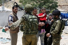 Binh sỹ Israel kiểm tra một gia đình Palestine tại một trạm kiểm soát ở Yatta, phía Nam Hebron. (Nguồn: EPA/TTXVN)
