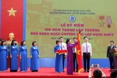 Chủ tịch Quốc Hội Nguyễn Thị Kim Ngân gắn Huân chương Độc lập hạng Nhất lên lá cờ truyền thống của Trường THCS Trưng Vương. (Ảnh: Quý Trung/TTXVN)