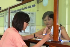 Hướng dẫn thủ tục cho người dân tại bộ phận một cửa Văn phòng Đăng ký đất đai Hà Nội tại quận Thanh Xuân, hà Nội. (Ảnh: TTXVN phát)