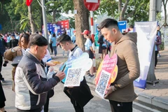 Khách hàng đang trải nghiệm mua bảo hiểm quét QRCode của VBI. (Ảnh: CTV/Vietnam+)