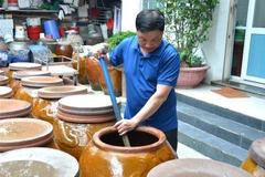Anh Bùi Thanh Phú kiểm tra nước mắm Hương Làng Cổ Nam Ô. (Ảnh: Quốc Dũng/TTXVN)