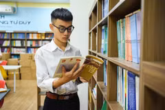 Nguyễn Viết Khôi Nguyên đọc sách tại thư viện trường Trung học phổ thông Nguyễn Văn Cừ. (Ảnh: TTXVN phát)