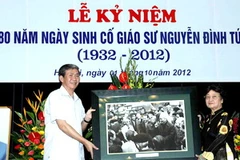 Trưởng ban Tuyên giáo Trung ương, Đinh Thế Huynh trao tặng bức ảnh có cố giáo sư Nguyễn Đình Tứ cho gia đình cố giáo sư. (Ảnh: Quý Trung/TTXVN)