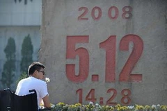 Một thanh niên bị mất cả hai chân trong trận động đất ở Tứ Xuyên đặt hoa tại đài tưởng niệm. (Nguồn: THX/TTXVN)