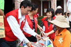Các tình nguyện viên Hội Chữ Thập đỏ trao hàng cứu trợ cho người dân vùng lũ lụt. (Ảnh: Hồ Cầu/TTXVN)